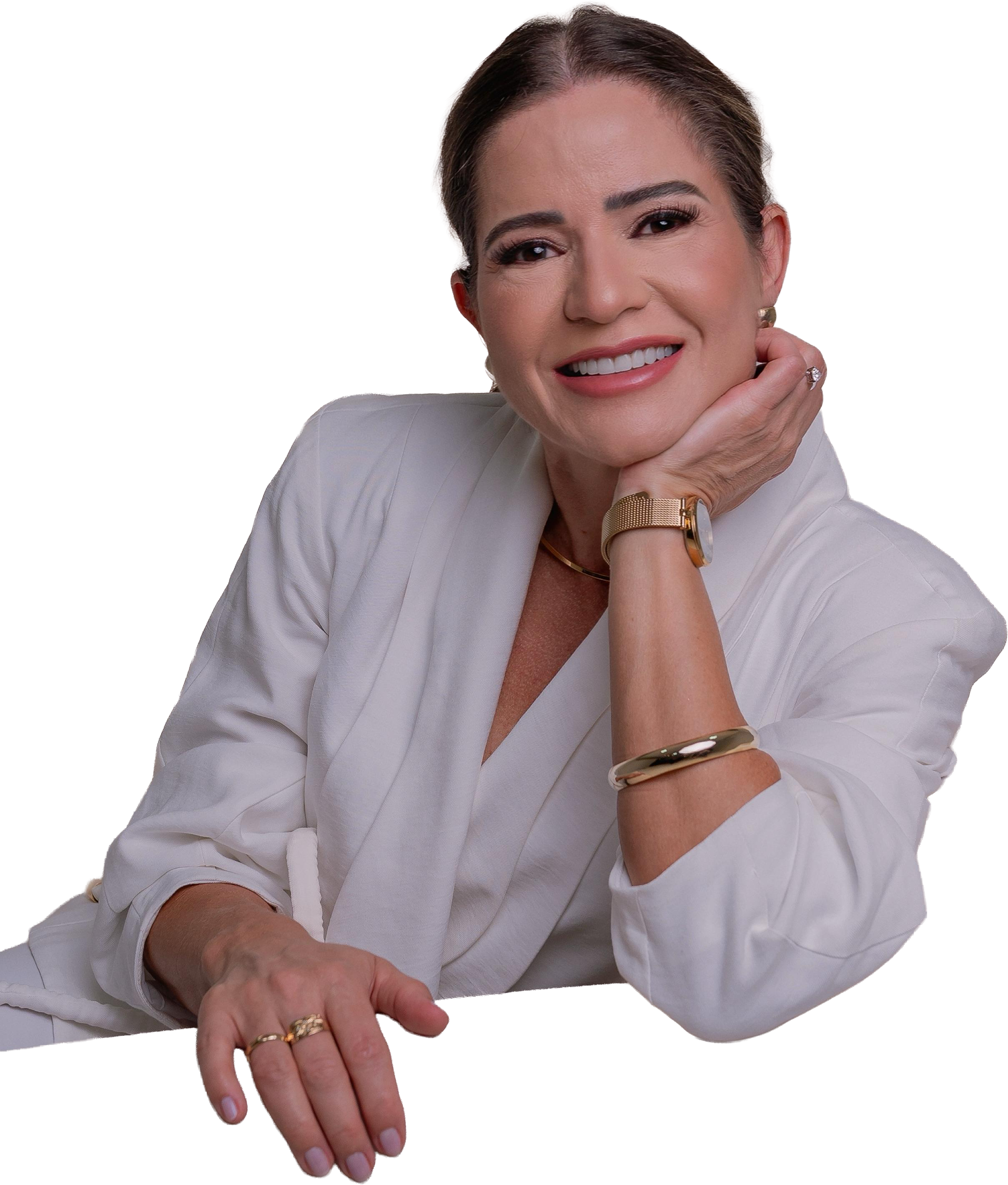 Foto da Dra. Valdirene Jacomo. Uma mulher loira de olhos pretos sorrindo com a mão ao queixo, jaleco branco e relógio de pulso dourado.